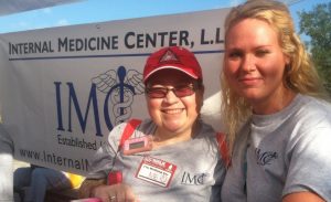 2 women standing in fron of IMC sign