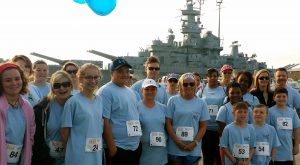 Man people in blue shirts and running numbers in front of a Battleship