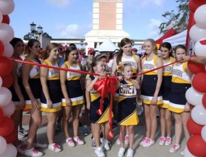 Young Warrior Cheerleaders gather around red and white balloons and a red ribbon