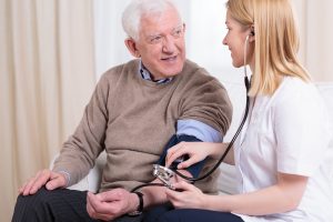 Doctor taking blood pressure of an older man