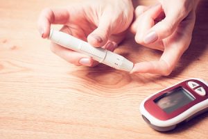 finger being pricked by Diabetes blood checker and a blood sugar reader