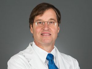 Picture of Edward G Carlos, MD wearing a white lab coat, a white shirt and a blue tie