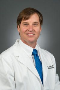 Picture of Edward G. Carlos, M.D. in a white lab coat and blue tie