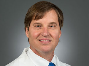 Picture of Edward G. Carlos, M.D. in a white lab coat and blue tie