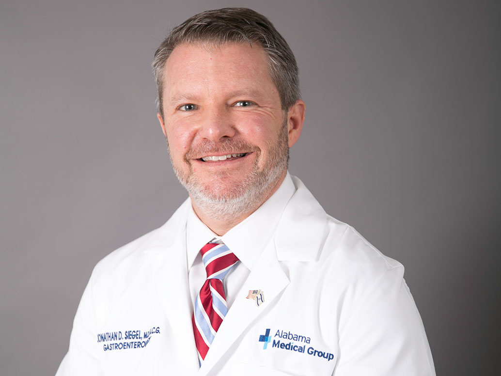 Picture of Jonathan Siegel, M.D., FACG in white lab coat and red and gray striped tie