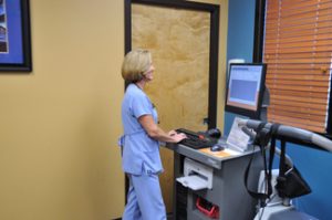 Picture of someone at a standing desk wearing purple scrubs