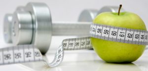 small tape measure with centimeters wrapped around an apple with a silver weight in the background